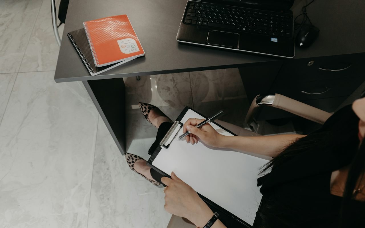 Buyer reviewing paperwork beside a laptop before comparing lubricant technical data sheets
